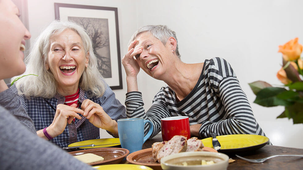 3 women laughing in a cafe over coffee